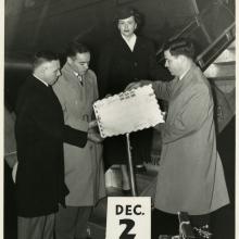 Three men and a woman in front of a Pan Am airplane