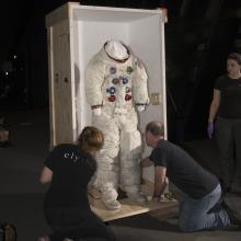 Buzz Aldrin's Apollo 11 spacesuit being moved out of the exhibit case in the "Apollo to Moon" gallery 