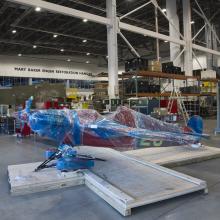 Red aircraft wrapped up in restoration hangar