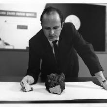 Man in suit looks at rock