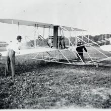 Black and white photograph of Wilbur Wright preparing his aircraft.