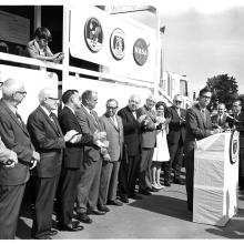 Group stands in front of tour trailer. 