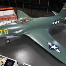 Side view of dark green military monoplane with one engine. Monoplane is on display in the museum.