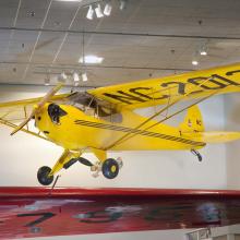 Yellow monoplane with one engine displayed as hanging in the Museum.