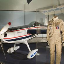 White airplane on display with flight suit next to it