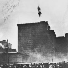 Cars below a building with a crashing airship