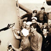 Crewmen draw submarine on side of ship