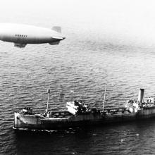 Blimp flying above merchant ship