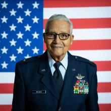 Man in military uniform in front of American flag