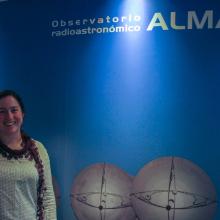 Image of Genevieve in front a sign for the ALMA observatory.