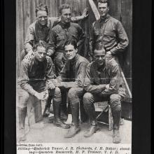 Three men stand behind three men sitting, all in uniform