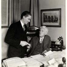 Two Men Exchange a Ticket Behind a Desk