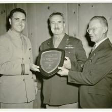 Two men present plaque to man between them