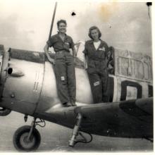 two women stand on wing of aircraft