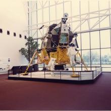 Lunar Module with protective railing on red carpet.