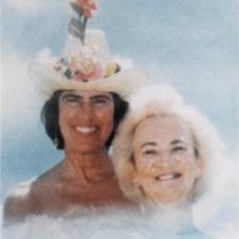 Two women in stylized clouds: Woman on the right has dark hair and is wearing a white cowboy hat with flowers sitting on the brim and pink hibiscus sticking out. Woman on right has white hair.