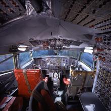 The cockpit of plane, including two seats and countless nobs and switches. 