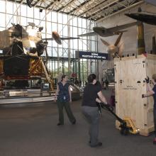 Gene Cernan's Apollo 17 spacesuit being moved out of the exhibit case in the "Apollo to Moon" gallery