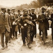 Black and white of Jules Vedrines wrapped in a leather flying suit and surrounded by others.