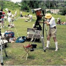 Man peers into a telescope at a large field. 