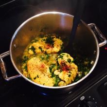 Chicken simmers in a pot on the stove.