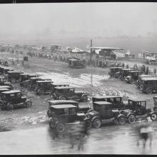 High level view of aircraft participating in the first Ford Commercial Airplane Reliability Tour lined up in rainy weather at the edge of the field 