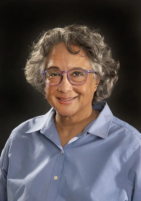 Curator Cathleen Lewis smiling wearing purple glasses.