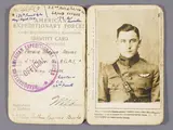 A manilla paper identification card, open to reveal a striking photograph of a young white man in a World War I military uniform. The left side of the page includes printed text reading "American Expeditionary Forces," handwriting including the name "Arthur Raymond Brooks" and "Flying Officer." Overtop the text is a purple circular stamp labeled "Official."