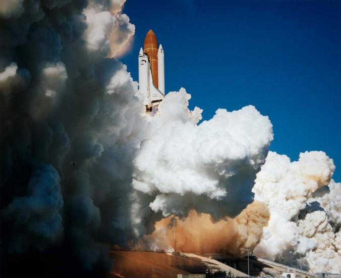 A rocket launches with a plum of smoke. 