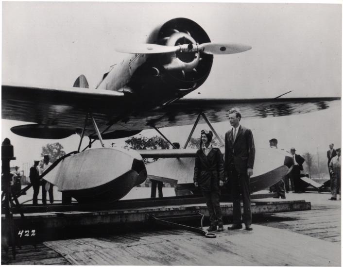 Two people standing in front of an aircraft