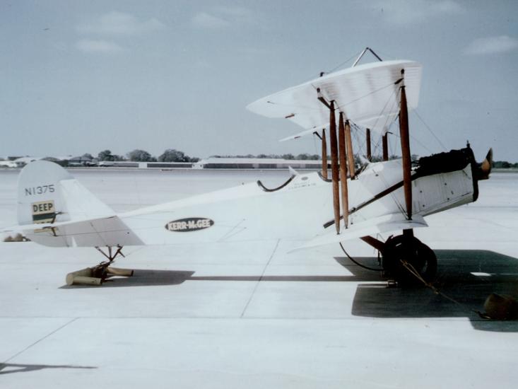 Lincoln-Standard H.S. (Modified Standard J-1) airplane on tarmac viewed from a side angle.