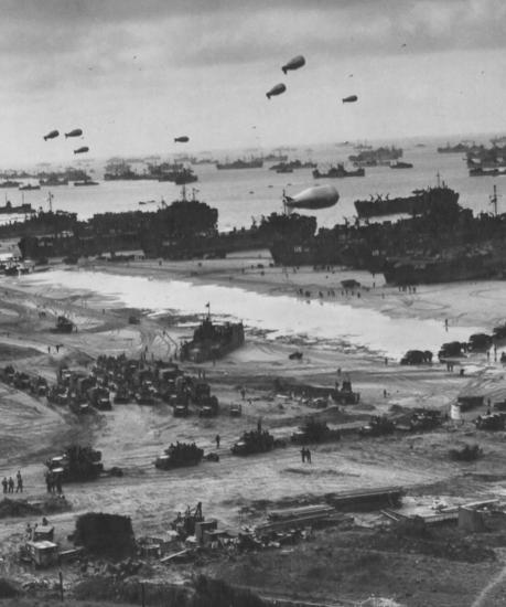 Zepplin shaped balloons float over tanks and more on a D-Day battlefield. 