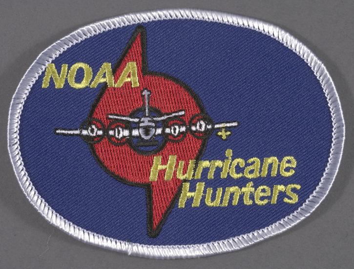 A patch with a plane flying through the symbol for a hurricane, accompanied by the text "NOAA Hurricane Hunters."