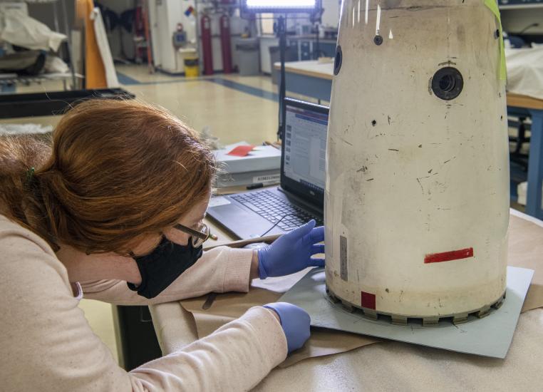 A woman examines a metal object. 