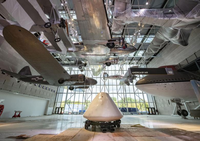 Command module Columbia sits in the middle of a museum gallery and surrounded by exhibits.