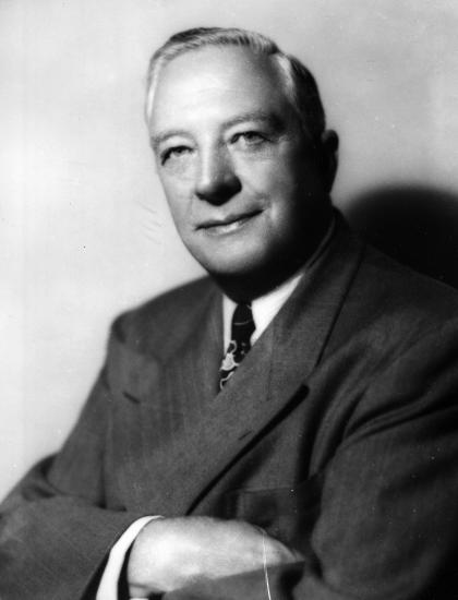 Thomas Braniff poses for a picture wearing a suit with his arms folded.