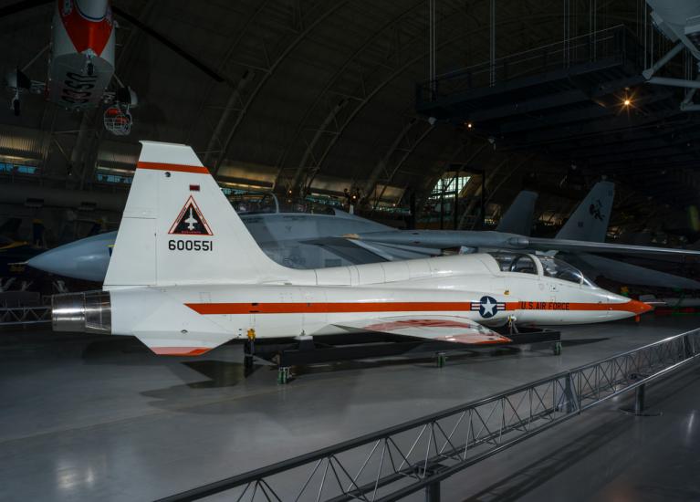 Rear view of a white and orange painted airplane in the museum hangar. 