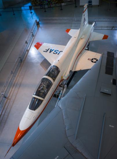 Overhead view of a white and orange painted airplane in the museum hangar.