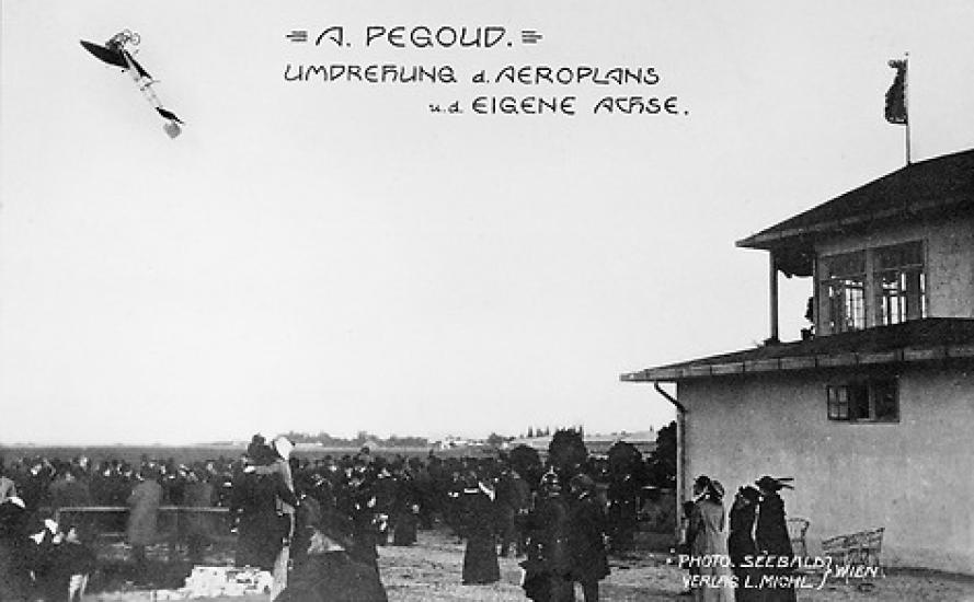 A crowd watching an airplane do a loop in the air. Text on the photo says "A. Pegoud, Umdrehung d. Aeroplans, u.d. Eigene Achse"