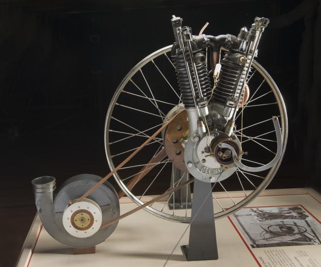 An engine that resembles a bicycle wheel made of metal, wood, and leather.