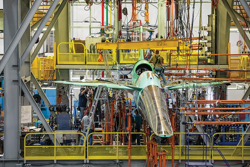 Lockheed Martin X-59 experimental aircraft in factory surrounded metal framing.