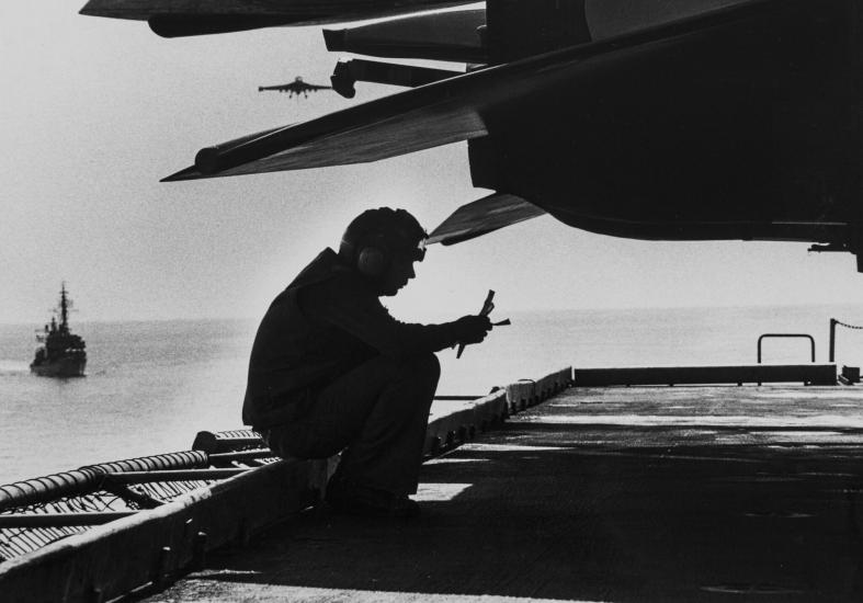 Silhouette of the back of an aircraft and a person sitting and reading something 