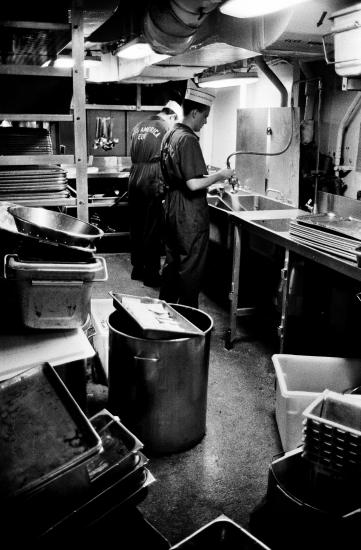 Two individuals in Naval uniform working in a kitchen 