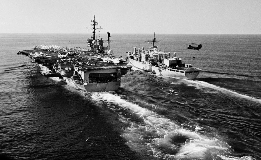 A boat next to an aircraft carrier in the ocean