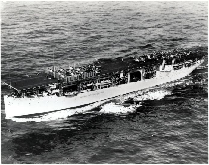 An old photograph of a long oval boat on the water. 