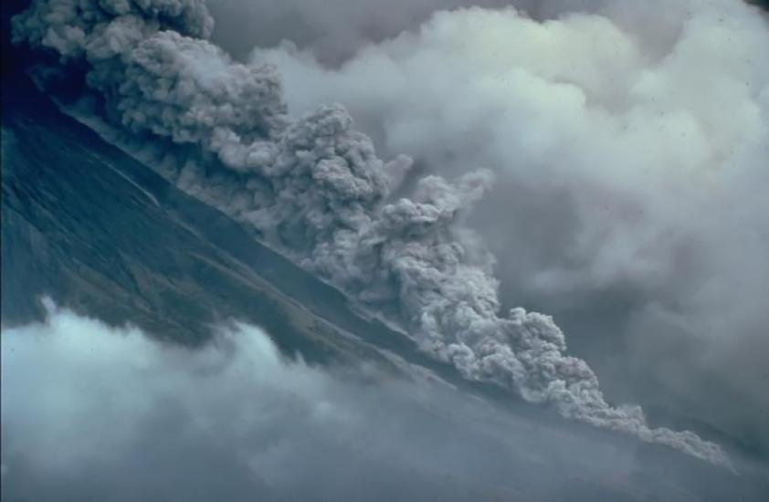 A large plume of hot ash, gases, and lava cascading down a mountain side. 