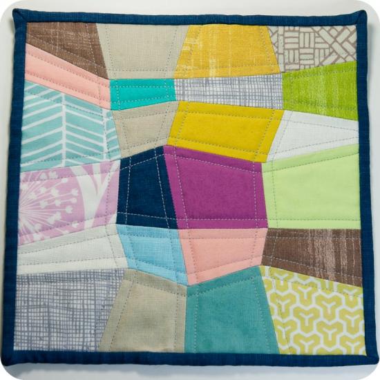 A small multicolored quilt composed of quadrilateral shapes. 