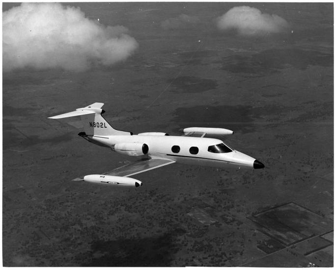 A side view of a small and sleek looking aircraft in flight, as if taken from the window of a nearby aircraft.