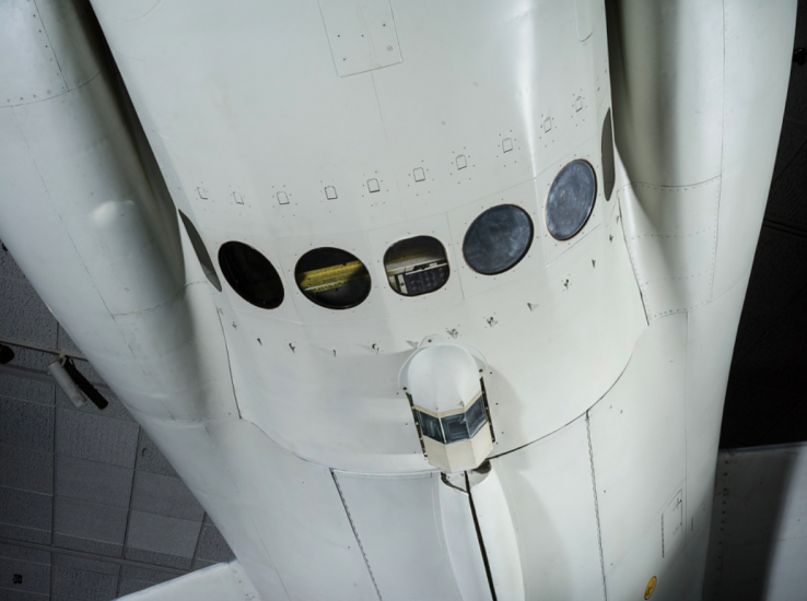 The white cylindrical body of a plane with seven round windows at the bottom.