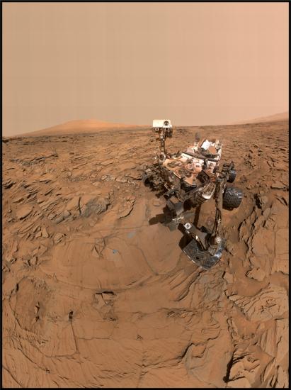 A rover takes a photograph on the orange, dusty martian surface. 